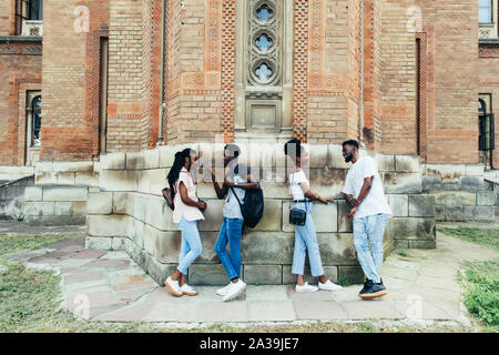 Il gruppo di allegro Allievi felici appoggiata sul muro bianco presso il campus. Internazionale il concetto di istruzione Foto Stock