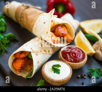 Pollo alla griglia si avvolge con ketchup ans salse crema, gustoso classico tortilla avvolge con carne di pollo e verdure Foto Stock
