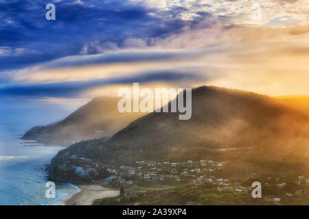 Gamma di gomma-tree coperto le colline sulla costa sud off Sydney parte del Grand Pacific conducente itinerario panoramico con il famoso Sea Cliff Bridge al tramonto dalla elevat Foto Stock