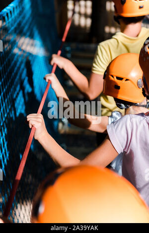 Vista ritagliata di bambini in arancione caschi in parco avventura Foto Stock