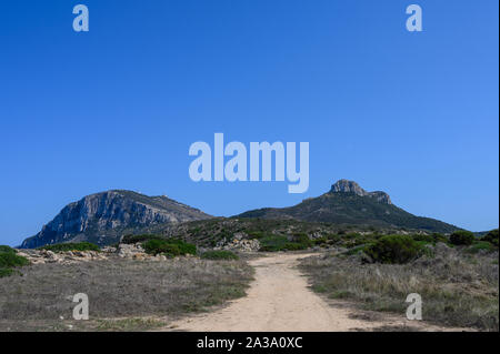 Strada va verso due alte montagne contro il cielo blu Foto Stock