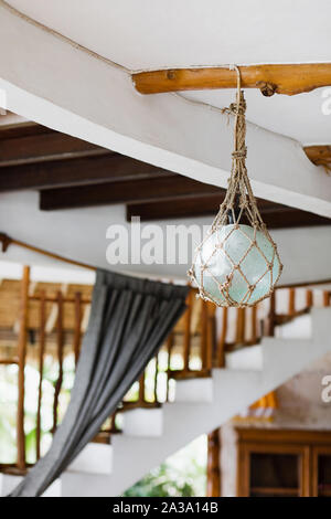 Eco Friendly interni in stile elemento di design. Lampada in vetro avvolto in craft corde appendere sul tetto di legno. VIlla in Bali. Foto Stock