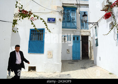 Una mezza età uomo tunisino in un business suit camminando attraverso le strade pedonali del quartiere Hafsia della medina (città vecchia) di Tunisi, Tunisia. Foto Stock