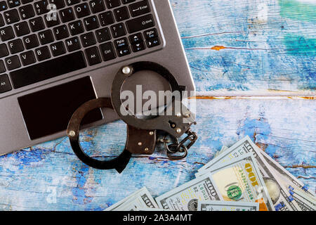 La polizia in manette su una pila di banconote da cento dollari con la tastiera del computer, tecnologia cyber crimine internet Foto Stock