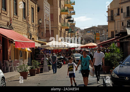 La gente camminare al di fuori del mercato di Ballaro a Palermo su una soleggiata giornata estiva. Sicilia, Italia. Foto Stock