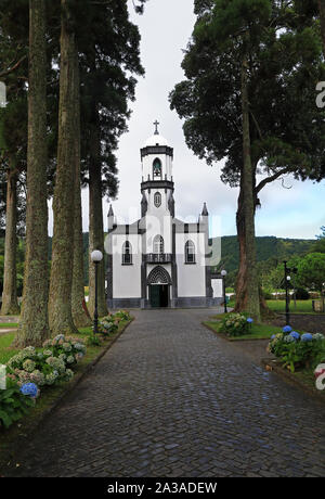 Bella chiesa di São Nicolau (Saint Nicolas) con un viale di alberi di alto fusto in Sete Cidades su São Miguel Island, Azzorre, Portogallo Foto Stock