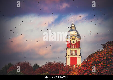 Vecchia torre con orologio della stazione ferroviaria della città di Varna, Bulgaria e uccelli in volo a sunrise immagine Foto Stock