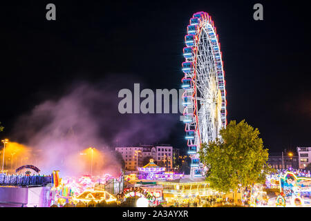 Stoccarda, Germania, 3 ottobre 2019, Canstatter wasen oktoberfest, una fiera illuminata di notte con molti giostra ruota grande e cibo offerte a Bad ca Foto Stock