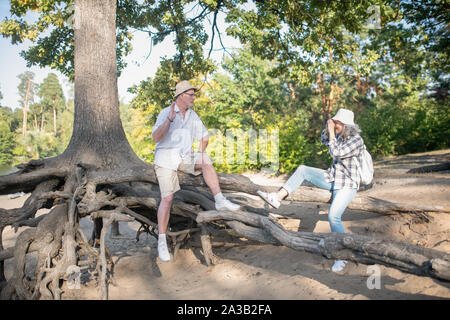 Amorevole moglie tenendo la foto del marito seduti sulle radici di albero Foto Stock