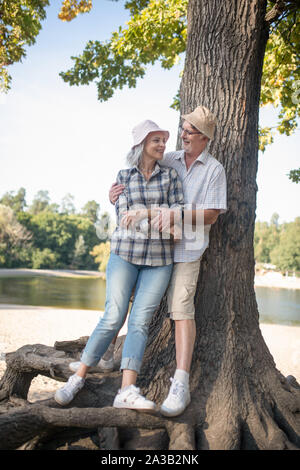 Cura uomo barbuto abbracciando la sua bella moglie in piedi vicino a tree Foto Stock