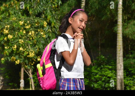 Carino Asian Studentessa nella preghiera che indossano uniformi scolastiche con libri Foto Stock