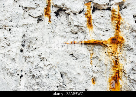 Un bianco muro di pietra con rusty bit di rebar sporgente. Foto Stock