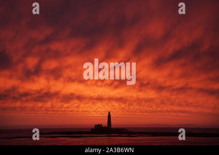 Un cielo rosso durante il sunrise a St Mary's Faro a Whitley Bay sulla costa nord est. Foto Stock