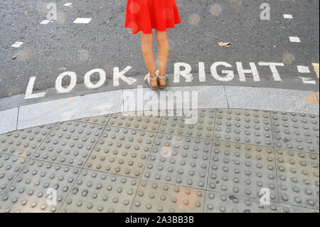 Pedone in piedi accanto alla strada tipico segno di attraversamento in Londra Foto Stock