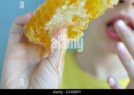 Immagine ravvicinata del favo di miele e gocciolamento con ragazza sfocate in background Foto Stock