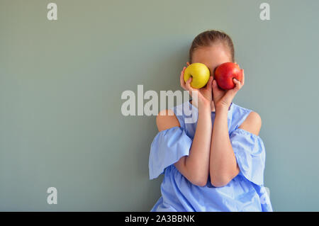 Ragazza con due mele davanti agli occhi Foto Stock