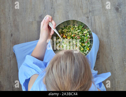Alta angolazione della ragazza di mangiare da una ciotola di insalata Foto Stock