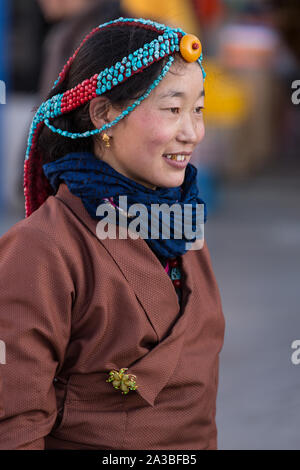 Un giovane Khamba donna tibetana del Kham regione del Tibet in pellegrinaggio a visitare luoghi santi in Lhasa, in Tibet. Ha un turchese & coral copricapo. Foto Stock