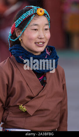 Un giovane Khamba donna tibetana del Kham regione del Tibet in pellegrinaggio a visitare luoghi santi in Lhasa, in Tibet. Ha un turchese & coral copricapo. Foto Stock