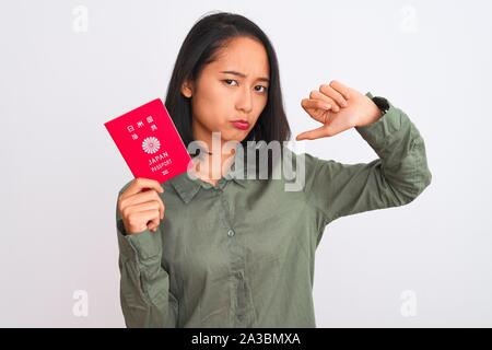 Bella donna cinese azienda giappone giapponese passaporto isolato su sfondo bianco con volto arrabbiato, segno negativo che mostra antipatia con il pollice verso il basso Foto Stock