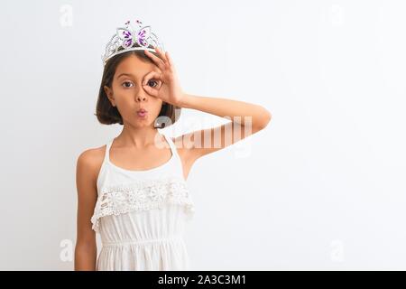 Bella ragazza bambino indossando princess crown in piedi isolato su sfondo bianco facendo ok gesto sconvolto con sorpreso per viso, occhi guardando attraverso Foto Stock