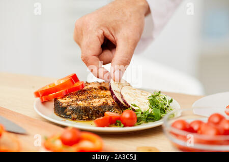 Close up di un irriconoscibile chef decorare deliziosa bistecca con verdure fresche, spazio di copia Foto Stock