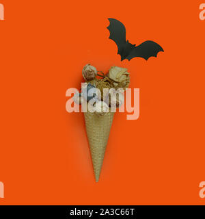 Cono gelato con un bouquet di fiori secchi e bat su sfondo arancione.vista superiore, laici piatta Foto Stock