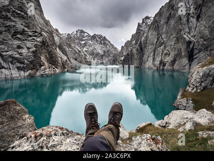 Marrone scarpe militari di un escursionista di fronte lago di montagna Kel Suu. Situato vicino al confine cinese in Kirghizistan Foto Stock