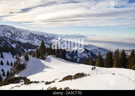 Gruppo di turisti stanno percorrendo a piedi il sentiero di neve al bellissimo sfondo con cielo nuvoloso. Arrampicata Outdoor Concept. Foto Stock