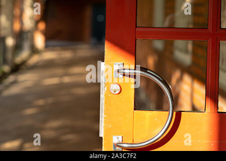 Curva maniglia in acciaio su un apri porta di legno alla luce del sole in una vista ravvicinata con spazio di copia Foto Stock