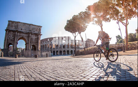 Felice giovane turista con moto indossando maglietta e cappello all arco di Costantino vicino al Colosseo a Roma, Italia di sunrise. Foto Stock