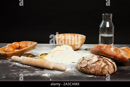 Immagine di sfondo di pane tradizionale rendendo gli ingredienti sul tavolo panificatori contro nero, spazio di copia Foto Stock