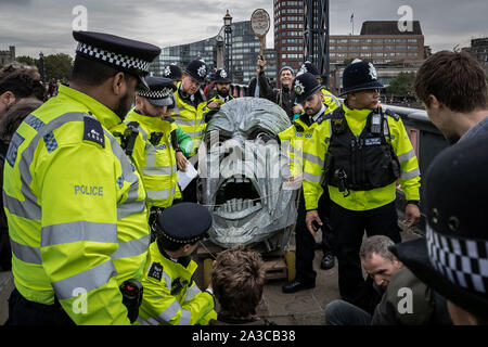 Londra, Regno Unito. Il 7 ottobre, 2019. La polizia grippare di parti del corpo di un gigante metallica di figura dalla ribellione di estinzione manifestanti durante una professione di Lambeth Bridge. Il attivisti ambientali iniziare una nuova ondata di azione di protesta questa mattina causando interruzioni a Londra. La Metropolitan Police ha confermato 21 arresti finora questa mattina. Credito: Guy Corbishley/Alamy Live News Foto Stock