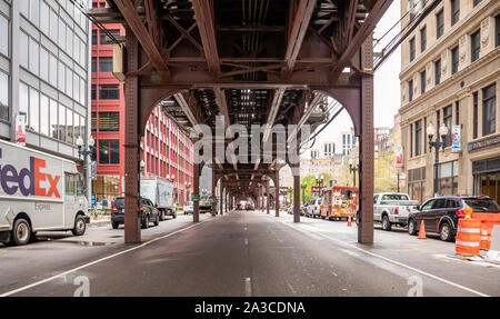 Chicago, Illinois, USA, 9 maggio 2019. Il traffico lungo la strada al di sotto e accanto a un ponte metallico con colonne. Il trasporto in città sullo sfondo. Foto Stock