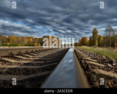 La strada ferrata contro lo sfondo di un azzurro cielo di autunno va all'infinito. Foto Stock