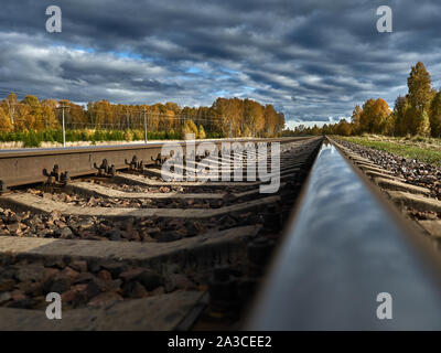 La strada ferrata contro lo sfondo di un azzurro cielo di autunno va all'infinito. Foto Stock