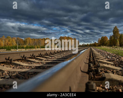 La strada ferrata contro lo sfondo di un azzurro cielo di autunno va all'infinito. Foto Stock
