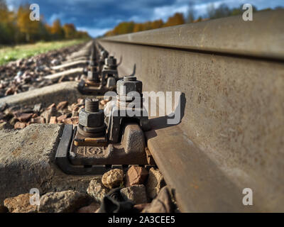La strada ferrata contro lo sfondo di un azzurro cielo di autunno va all'infinito. Foto Stock