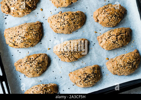 In casa la pasticceria turco Pogaca fatta con grano Karakilcik, Formaggio con nero Semi di cumino sulla carta da forno. Alimenti biologici. Foto Stock