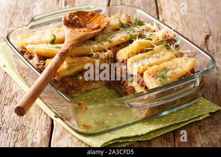 Il taglio di un pezzo di lasagna di Puerto Rican chiudere pastelon fino in una teglia sul tavolo orizzontale. Foto Stock