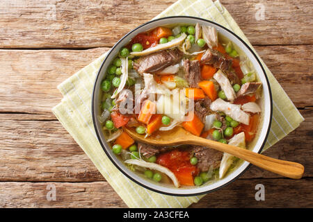 Spesso cotte lentamente la zuppa a base di verdure e carne di close-up in una piastra sul tavolo. Parte superiore orizzontale vista da sopra Foto Stock