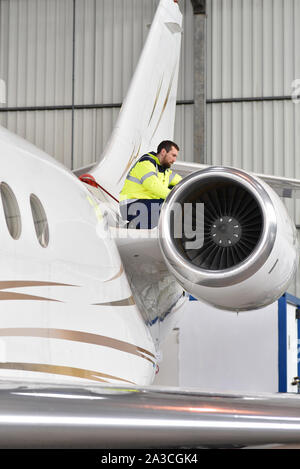 I lavoratori aeroportuali controllare un aereo per la sicurezza in un hangar Foto Stock