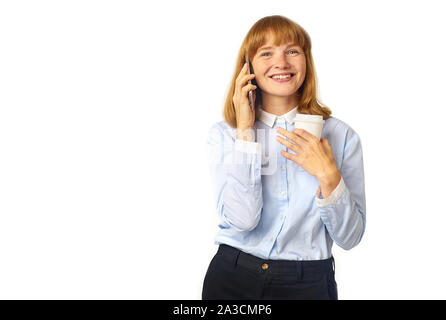 Ritratto di giovane donna redheaded con lentiggini e bang a parlare su un telefono sorridente e tenendo una tazza di caffè nelle sue mani Foto Stock