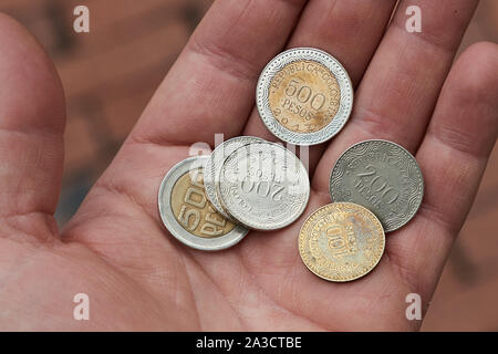 In pesos colombiano monete trattenute in mano Foto Stock