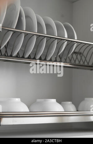 Piatto di metallo di essiccazione rack con grande bianco nizza pulire le piastre. Tradizionale cucina confortevole. Aprire il piatto bianco svuotamento armadio con wet piatti di vetro e Foto Stock