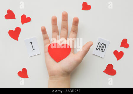 Padri giorno concetto. Messaggio di carta con il cuore in mano per bambini su sfondo bianco. Vista dall'alto. Compleanno Foto Stock