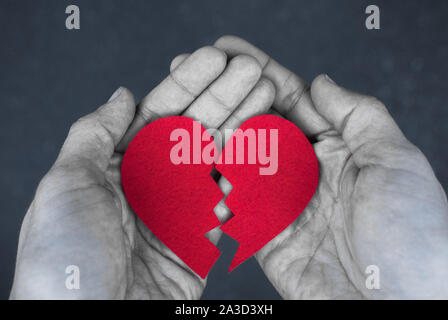 Cuore spezzato nelle mani - Concetto di divorzio. foto in bianco e nero con cuore rosso. Blak e bianco Foto Stock