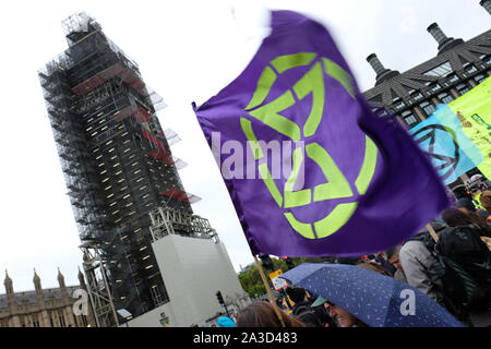 Westminster, London, Regno Unito - Lunedì 7 Ottobre 2019 - Un'estinzione della ribellione XR bandiera sventola sotto la pioggia sul Westminster Bridge accanto al Big Ben. Foto Steven Maggio / Alamy Live News Foto Stock