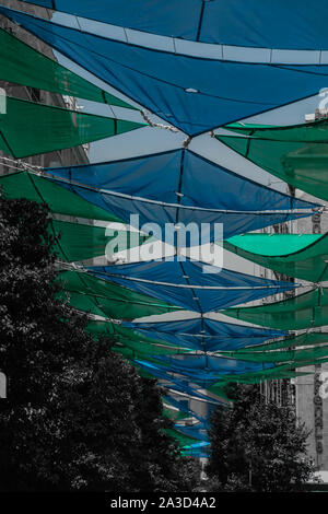 Una foto evidenziando il colorato coperture solari che decorano una strada in Madrid. Foto Stock