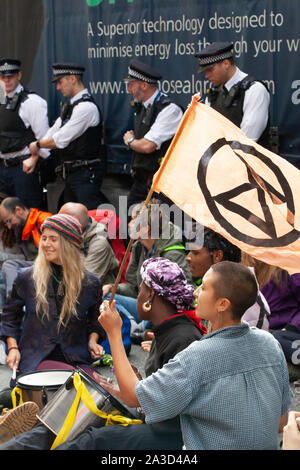 Stadio di persone un sit-in con il canto e la musica al di fuori di DEFRA come estinzione della ribellione ha iniziato da due settimane di protesta contro l'inazione oltre la crisi climatica in Westminster con numerosi blocchi stradali, incluso Westminster e ponti di Lambeth. Le proteste al di fuori del Parlamento, l'Abbazia di Westminster, Downing Street e DEFRA ha portato in tutta la zona essendo chiusa al traffico. Foto Stock